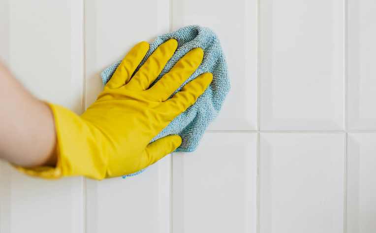 image of hand cleaning white tile backsplash